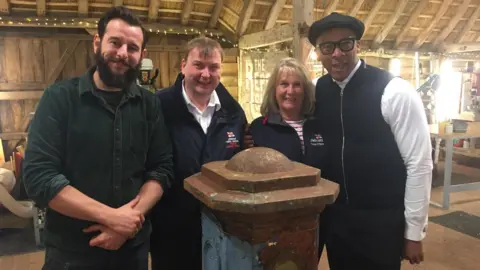 RNLI/Penlee Volunteers Elaine Bawden and Martin Brockman with Jay Blades and Dominic Chinea behind restored collection box