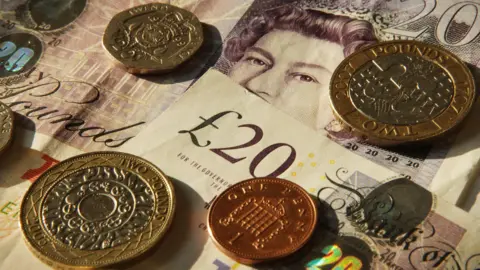 A close up of sterling pound notes and coins.