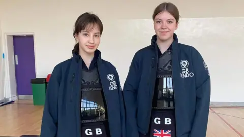 Andy Lomas Keira (left) and Chloe pictured smiling while wearing their Team GB Kendo uniform