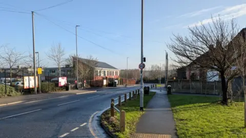 David Spereall/BBC An empty suburban road with a 20mph sign on a lamp-post. It is a sunny day and other street furniture can be seen.