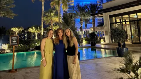 A group of women stood in front of a swimming pool. The Burj Khalifa sits in the background.