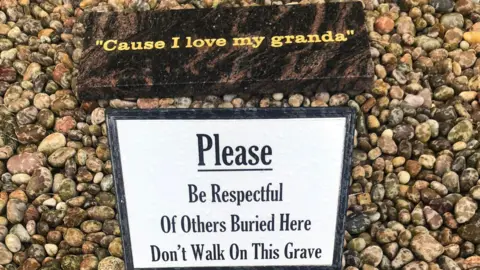A sign reads: 'Please Be Respectful Of Others Buried Here Don't Walk On This Grave'