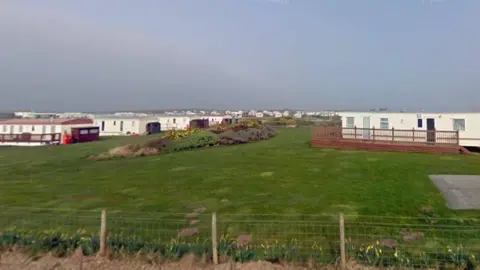 Google A fence surrounded by daffodils with caravans in the distance at South End Caravan Park