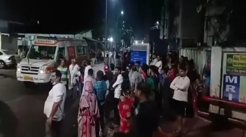 Men and women gather near an ambulance outside the hospital building where the fire incident took place.