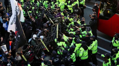 Reuters Pengunjuk rasa anti-Yoon bentrok dengan petugas polisi saat mereka berjalan menuju kediaman resmi Presiden Korea Selatan Yoon Suk Yeol yang dimakzulkan