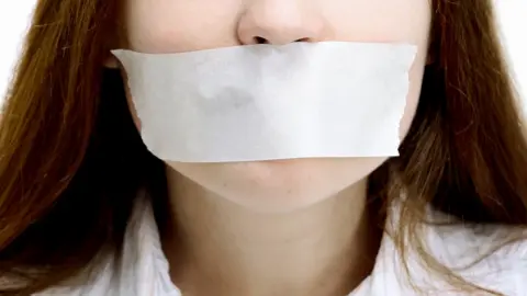 BBC Woman with tape over her mouth