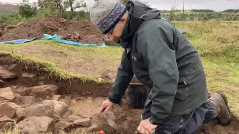 BBC Archaeologists uncovering the walls of Bedrule Castle.