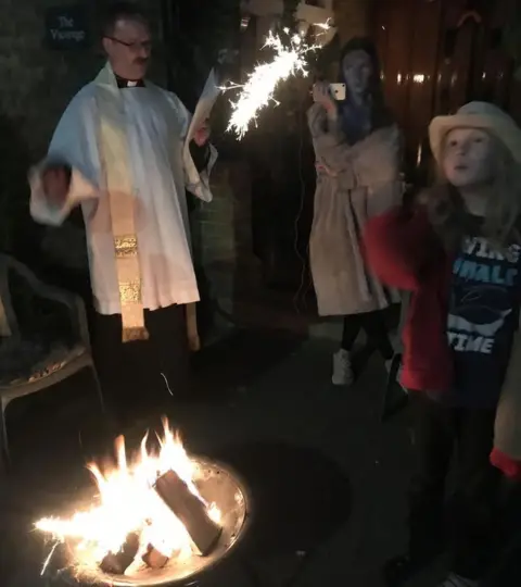 Rachel Summers Rachel and her family hold candles and sparklers whilst standing around a fire in their garden