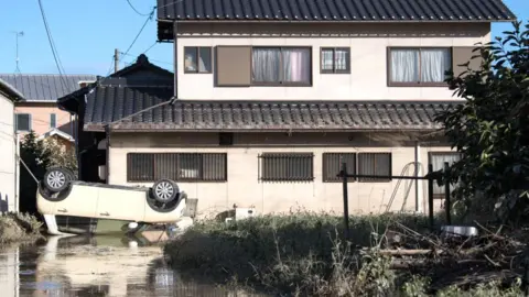 Getty Images A car lies upside down following heavy flooding, on July 8, 2018 in Kurashiki near Okayama, Japan