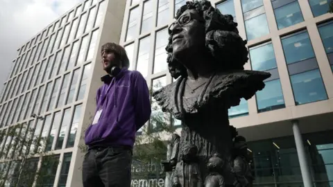 BBC Johnny Giles standing beside the bronze stature of Betty Campbell in Cardiff