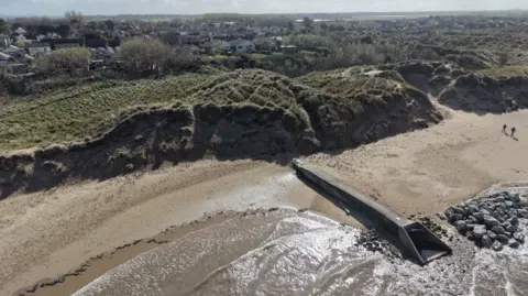 Sefton Council Aerial shot of a large sanddune and a beach.