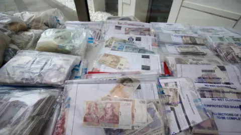 PA Images Cash seized in raids on display during a press briefing at the Scottish Crime Campus in Gartcosh, Lanarkshire.