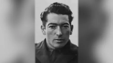 Contributed A black and white image of a soldier. He has dark hair and wears a jacket with a shirt and tie underneath. 
