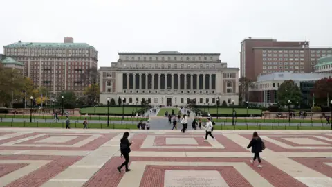 Getty Images People walk on side walk outside university building