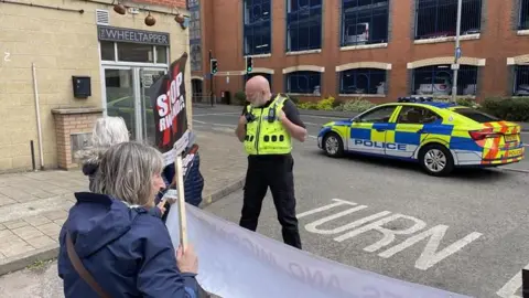 Protestors have stopped two vans leaving the centre in Loughborough after they learned people were being detained 