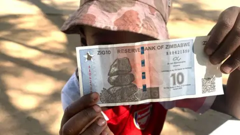 Farai Sevenzo A child holding  up one of the first Zig notes to go into circulation - Friday 3 May 2024