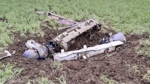 Deborah Coleman Grey-coloured parts from a Typhoon jet laying in a field covered in mud