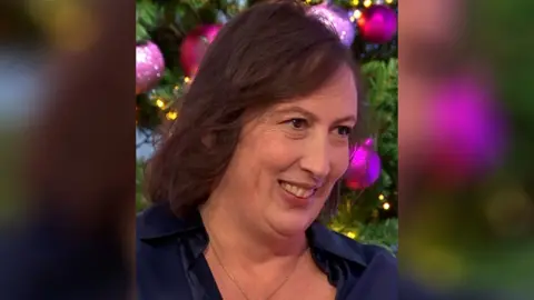 Miranda Hart smiles in front of a Christmas tree