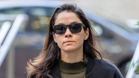 Shivon Zilis wearing sunglasses, a dark blue jacket and a dark green jumper