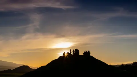 Mike Bolam A sunrise at the Crawick Multiverse with light breaking through the rock artwork on top of a hill