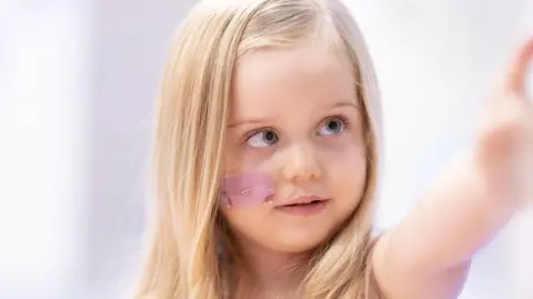 UCLH A close up of Seren who has blue eyes and long, blonde hair. She is pointing at something.