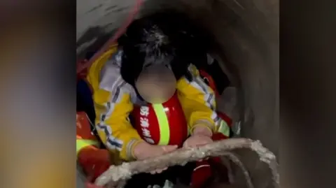 A little girl on the back of a rescue worker
