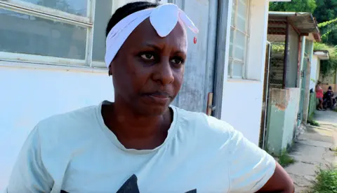 BBC Yusely, a woman wearing a T-shirt and white headband, looks at the camera