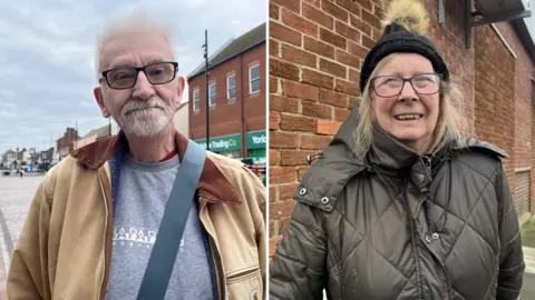 Louise Hobson/BBC Simon Overton is stood in Redcar high street with the Yorkshire Trading Company building behind his right shoulder. He has white hair and is wearing a beige jacket. Carol has glasses, shoulder-length blonde hair and a fluffy bobble hat. She wears an olive-coloured warm jacket.