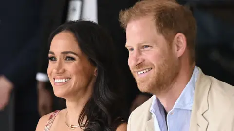 Getty Images Close up of Harry and Meghan sat next to each other smiling.