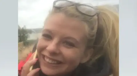 Police Scotland A young woman with blonde hair and a mobile phone held to her right ear smiles at the camera