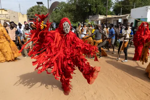 JEROME FAVRE / EPA People dressed in red, tasselled costumes dance as a part of a masquerade.