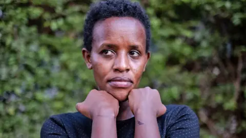 Agather Atuhaire displays bruises and scars on her wrists after her release from detention by Tanzanian authorities, outside a hospital in Kampala - 23 May 2025.