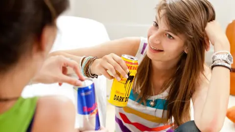 Science Photo Library Teenage girls drinking energy drinks