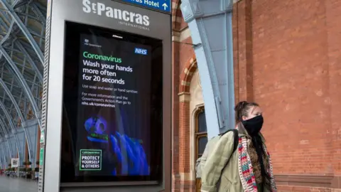 In Pictures / Getty Images A woman leaving St Pancras International station wearing a mask