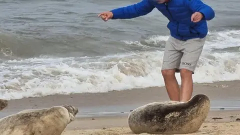 Friends of Horsey Seals Man by a seal