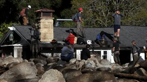 Getty Images Rescuers on roof of house buried by mudslide in California. 10 Jan 2018