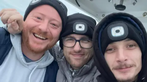 Lee Williams Three white men smiling and wearing black beanie hats