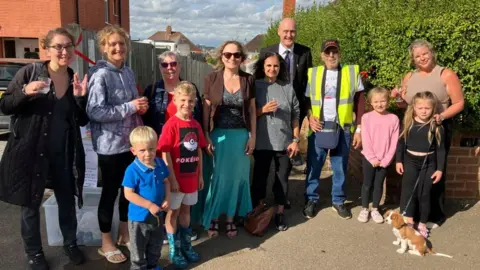 James Grant/ BBC A small group of residents gather in the newly paved lane