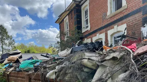 Thomas Magill/BBC A close-up of the fly-tipped rubbish piled up in front of the house.