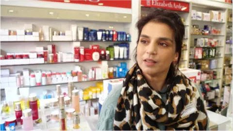 BBC London Farah Ali, local pharmacist, standing at the till