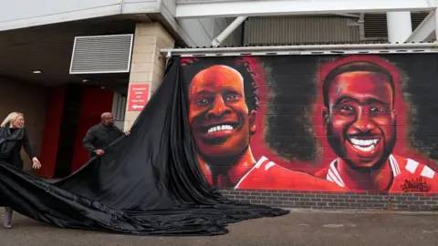 Middlesbrough Football Club Spray painted artwork on a brick wall depicts players Ugo Ehiogu and Sol Bamba in their red and white uniform.