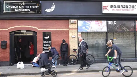 Mick tries to help the man outside the church entrance