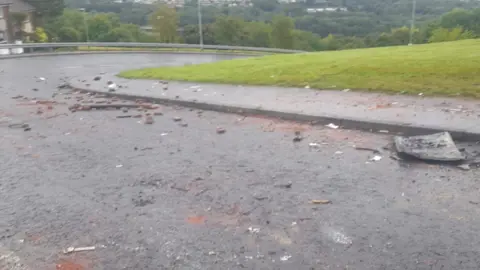 bricks and other debris lies across Southway, a road in the Creggan estate in Derry, where police officers were attacked. It is early morning, the morning after the attack on officers