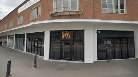A bar on a street corner with a gold neon sign saying 'Vaal & Vaal'.