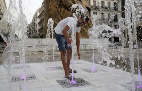 Billel Bensalem/Getty Images A man cools off at a splash pad.