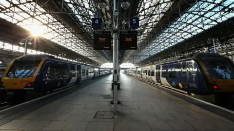 Two Northern trains sit parked at the platforms of Manchester Piccadilly station.