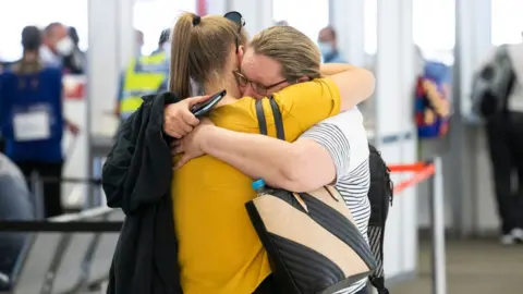 Getty Images Two family members hug after reuniting at Perth Airport in December 2020 after state border closures were eased