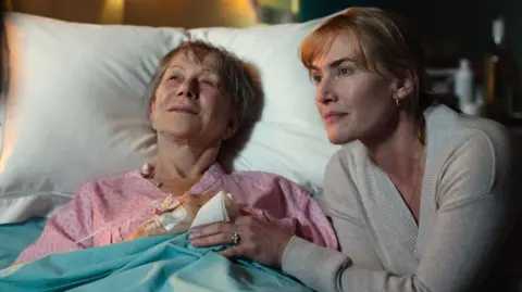 Netflix Dame Helen Mirren stars alongside Winslet - Dame Helen is lying in a hospital bed with Winslet at her side.