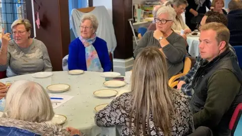 Le Dr James Brown et le Dr Matt Ash assis autour d'une table avec des soignants de personnes atteintes de démence, dans un groupe de soutien dans l'Essex. 