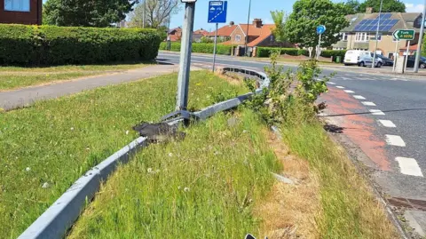 A crash barrier bent out of shape on a road bend.